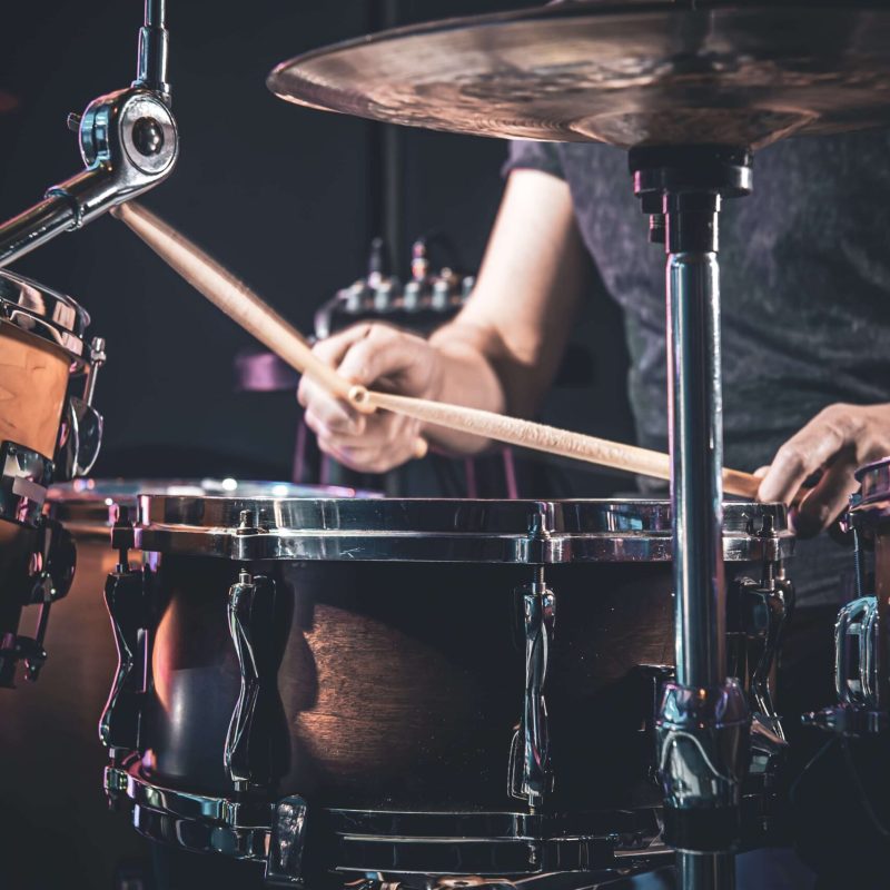 male-drummer-plays-drums-dark-room-min